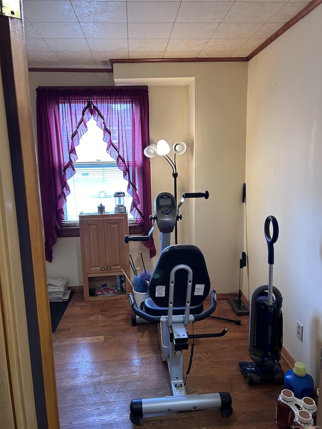 workout area with ornamental molding, baseboards, and hardwood / wood-style floors