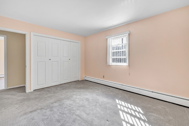 unfurnished bedroom with light carpet, a closet, and a baseboard heating unit