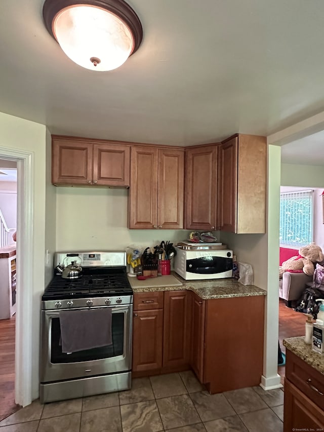 kitchen with light stone counters, stainless steel range with gas cooktop, and light tile patterned flooring