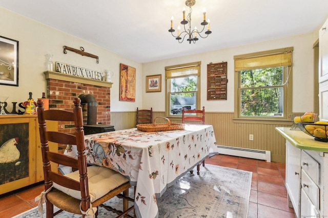 dining area with an inviting chandelier, light tile patterned floors, a wood stove, and a baseboard heating unit