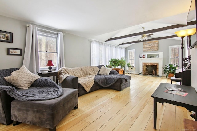 living room with ceiling fan, a fireplace, lofted ceiling with beams, and light wood-type flooring