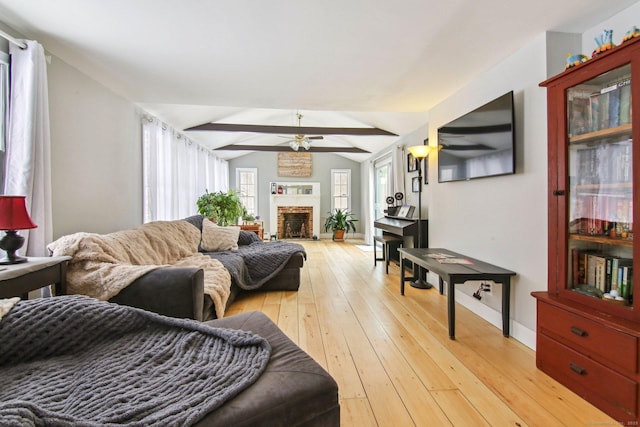 living room featuring ceiling fan, light hardwood / wood-style floors, a brick fireplace, and vaulted ceiling with beams