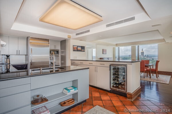 kitchen featuring a tray ceiling, dark wood-type flooring, built in appliances, and wine cooler