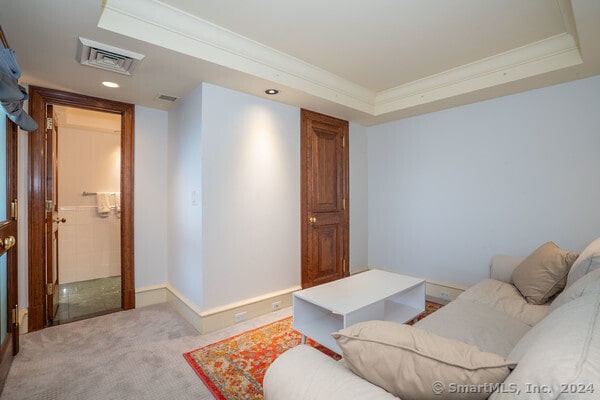 carpeted living room featuring a raised ceiling and crown molding