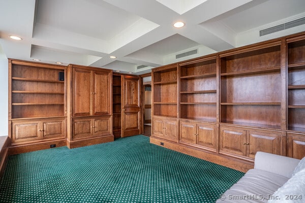 interior space featuring coffered ceiling, beamed ceiling, and dark colored carpet