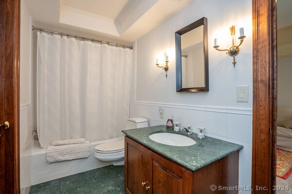 full bathroom featuring shower / bath combination with curtain, vanity, a raised ceiling, and toilet