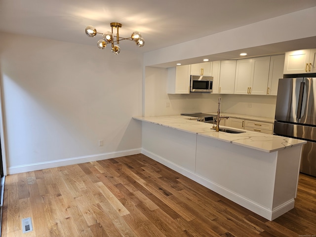 kitchen featuring light stone counters, kitchen peninsula, light hardwood / wood-style flooring, white cabinetry, and stainless steel appliances