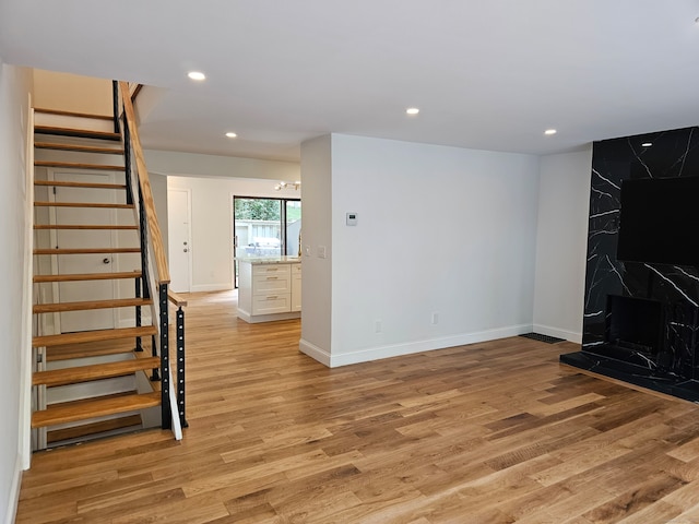 unfurnished living room featuring a high end fireplace and light hardwood / wood-style floors