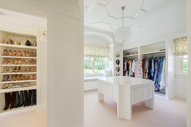 walk in closet with light carpet and a chandelier