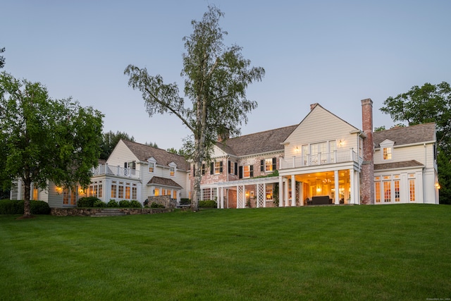 back house at dusk featuring a yard and french doors