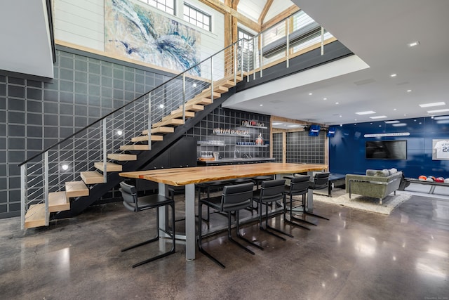 interior space featuring bar area, concrete flooring, and a towering ceiling