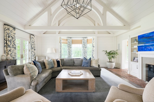 living room featuring a notable chandelier, wooden walls, french doors, vaulted ceiling with beams, and dark wood-type flooring