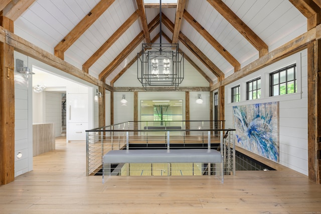 interior space featuring hardwood / wood-style floors, high vaulted ceiling, wood walls, and a notable chandelier