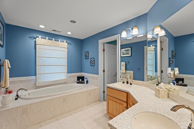 bathroom with tile patterned flooring, tiled bath, and vanity