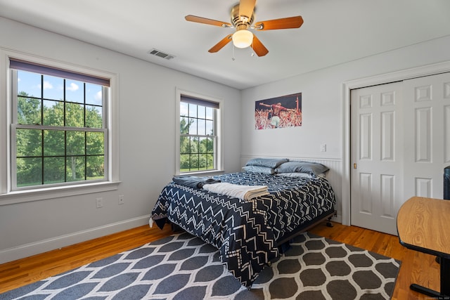 bedroom with wood-type flooring, ceiling fan, and a closet