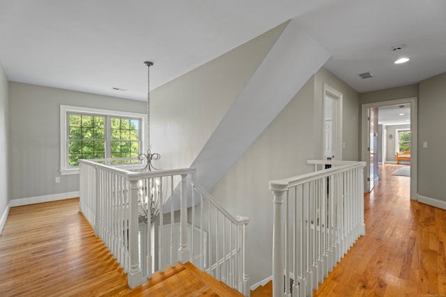 stairway with hardwood / wood-style floors and an inviting chandelier