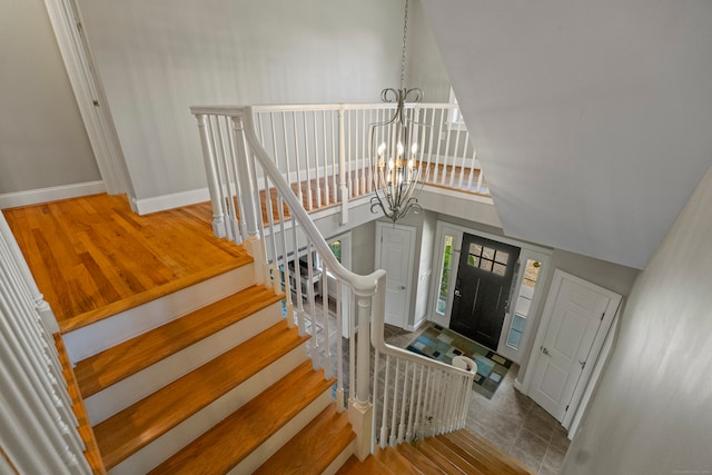 stairs featuring hardwood / wood-style floors, a high ceiling, and a notable chandelier