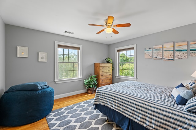 bedroom featuring ceiling fan, wood-type flooring, and multiple windows