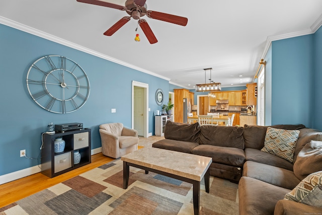 living room featuring light wood-type flooring, crown molding, sink, and ceiling fan