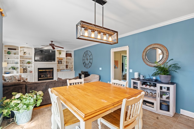 tiled dining area with built in features, ceiling fan, and ornamental molding