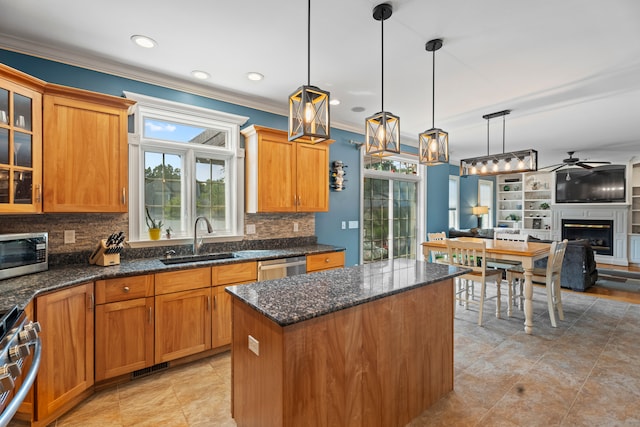 kitchen featuring ornamental molding, stainless steel appliances, sink, a center island, and ceiling fan