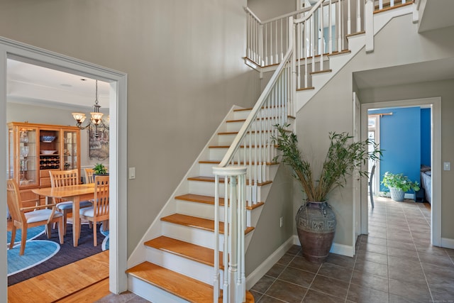 staircase with wood-type flooring and an inviting chandelier