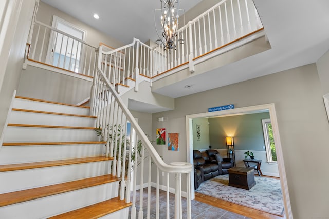 stairway with a towering ceiling, a chandelier, and hardwood / wood-style flooring