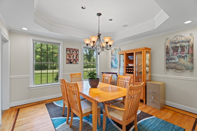 dining space with light wood-type flooring, ornamental molding, and a tray ceiling