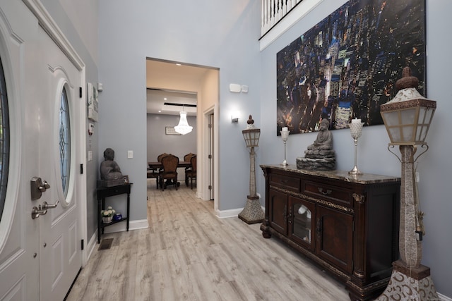 hallway with a towering ceiling and light hardwood / wood-style flooring