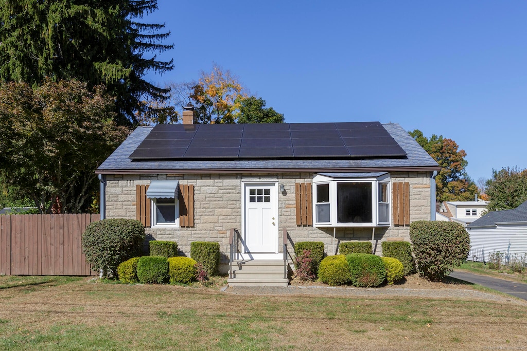 view of front of home with solar panels and a front lawn