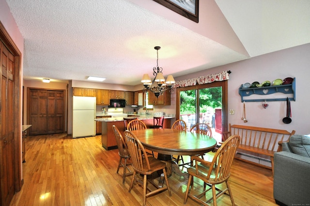 dining space featuring lofted ceiling, light wood-type flooring, a textured ceiling, a baseboard radiator, and a chandelier