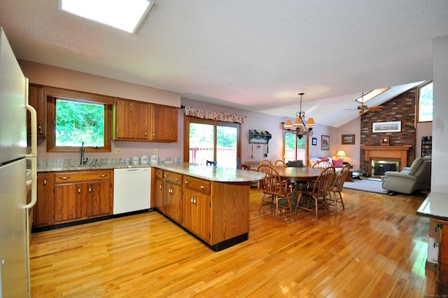 kitchen featuring light hardwood / wood-style flooring, kitchen peninsula, lofted ceiling, white appliances, and ceiling fan with notable chandelier