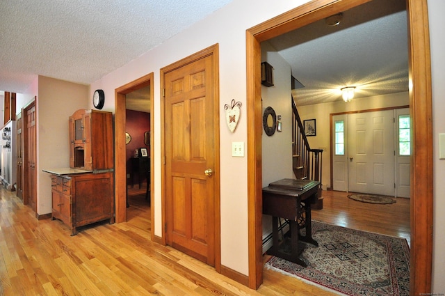 hall featuring a textured ceiling and light hardwood / wood-style flooring