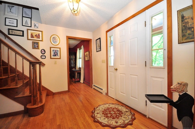 foyer entrance with a textured ceiling, hardwood / wood-style flooring, and a baseboard radiator