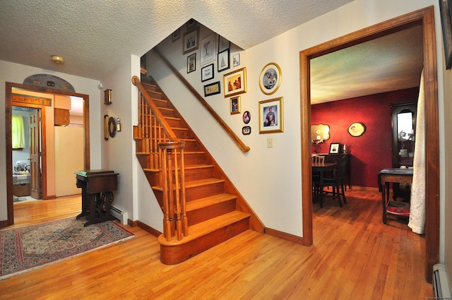 stairs with a textured ceiling, hardwood / wood-style flooring, and baseboard heating