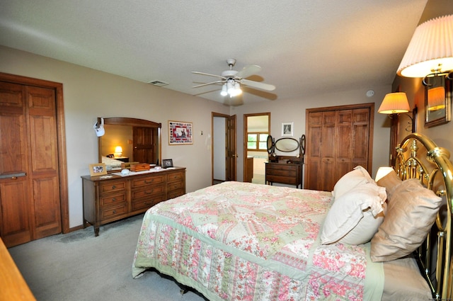 bedroom featuring light carpet, a textured ceiling, ceiling fan, and multiple closets