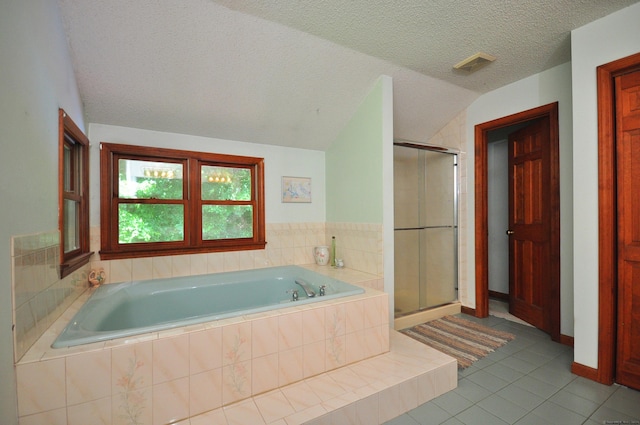 bathroom featuring tile patterned flooring, lofted ceiling, a textured ceiling, and independent shower and bath