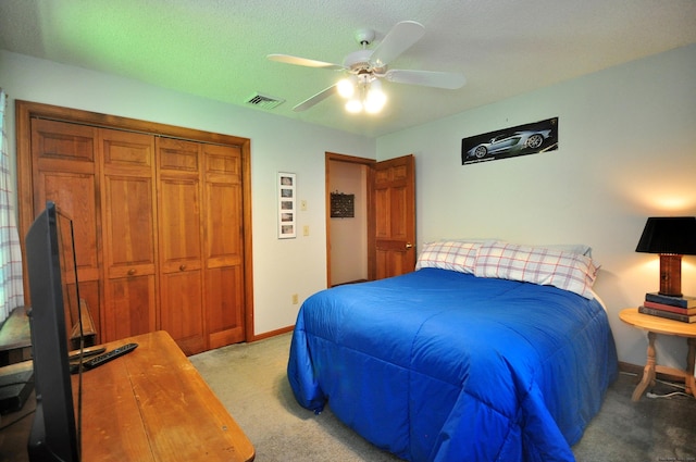 carpeted bedroom featuring ceiling fan, a textured ceiling, and a closet