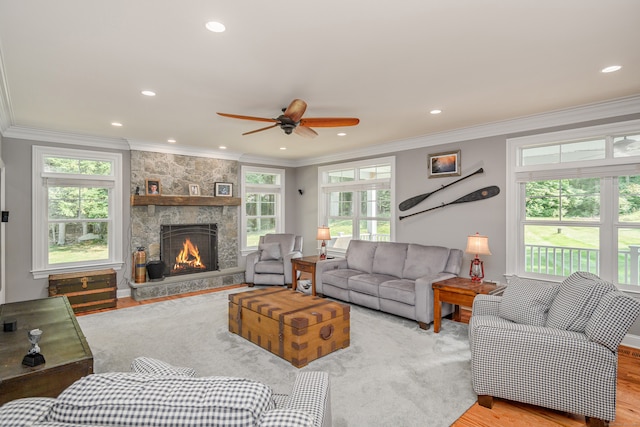 living room featuring ceiling fan, light hardwood / wood-style flooring, a wealth of natural light, and a fireplace