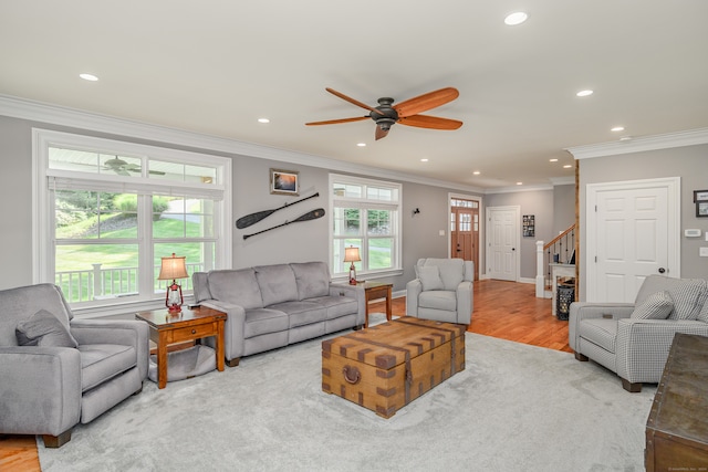 living room with light hardwood / wood-style floors, crown molding, and ceiling fan