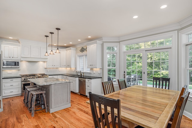 kitchen with a center island, white cabinetry, decorative light fixtures, and stainless steel appliances