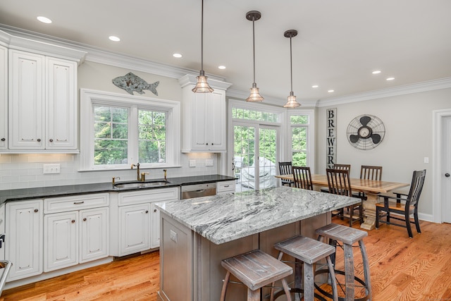 kitchen with sink, a kitchen island, decorative backsplash, and light wood-type flooring