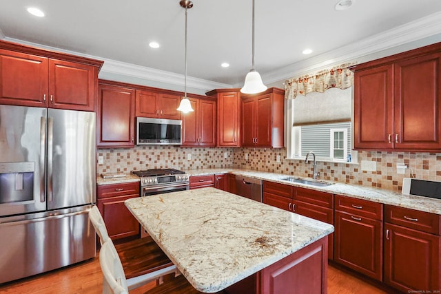 kitchen featuring a kitchen island, sink, appliances with stainless steel finishes, decorative light fixtures, and a kitchen breakfast bar