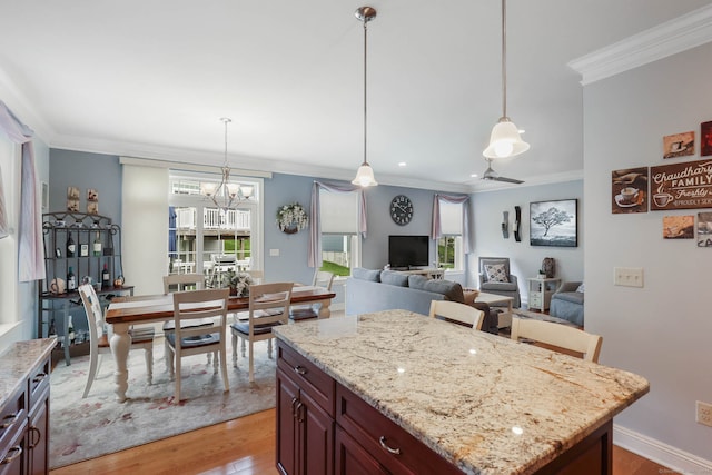 kitchen with pendant lighting, ornamental molding, a kitchen island, and light wood-type flooring