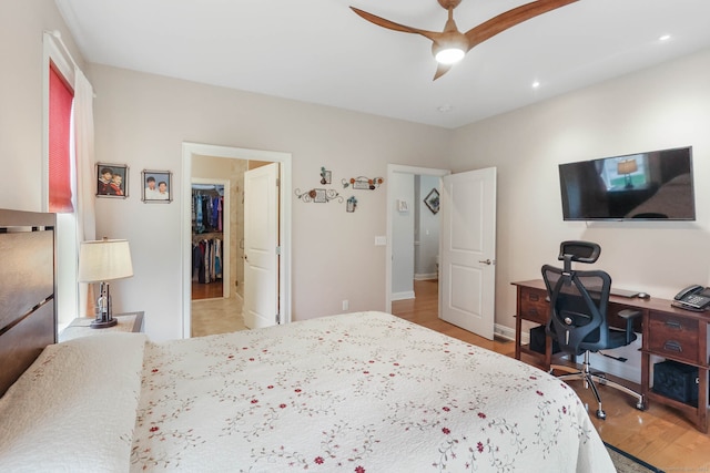 bedroom with ceiling fan, light wood-type flooring, a closet, and a spacious closet