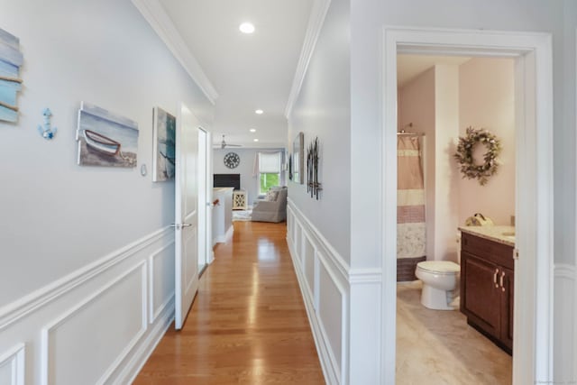 corridor with ornamental molding and light hardwood / wood-style floors