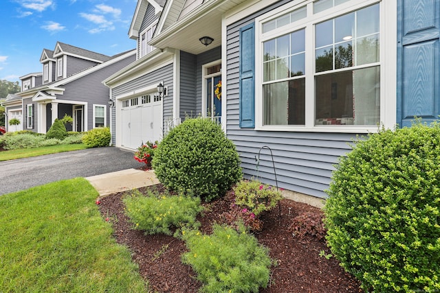 entrance to property featuring a yard and a garage