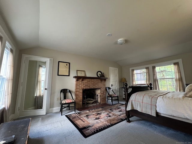 carpeted bedroom featuring vaulted ceiling and a fireplace