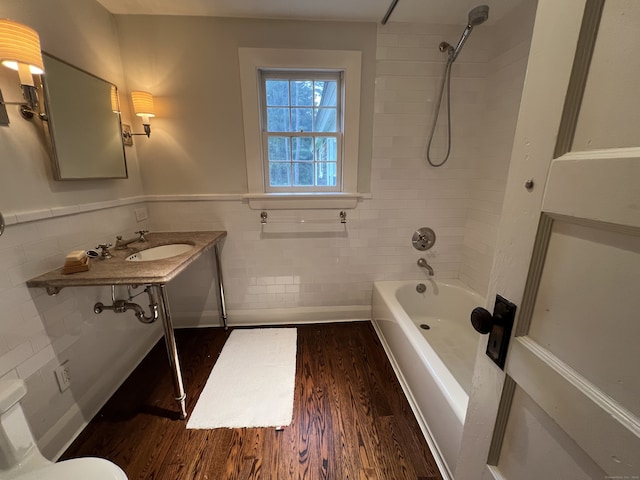 full bathroom featuring tile walls, tiled shower / bath combo, sink, hardwood / wood-style flooring, and toilet