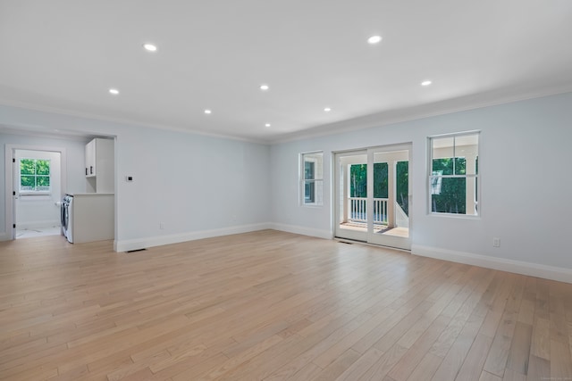 unfurnished living room featuring washer / dryer, ornamental molding, and light hardwood / wood-style flooring